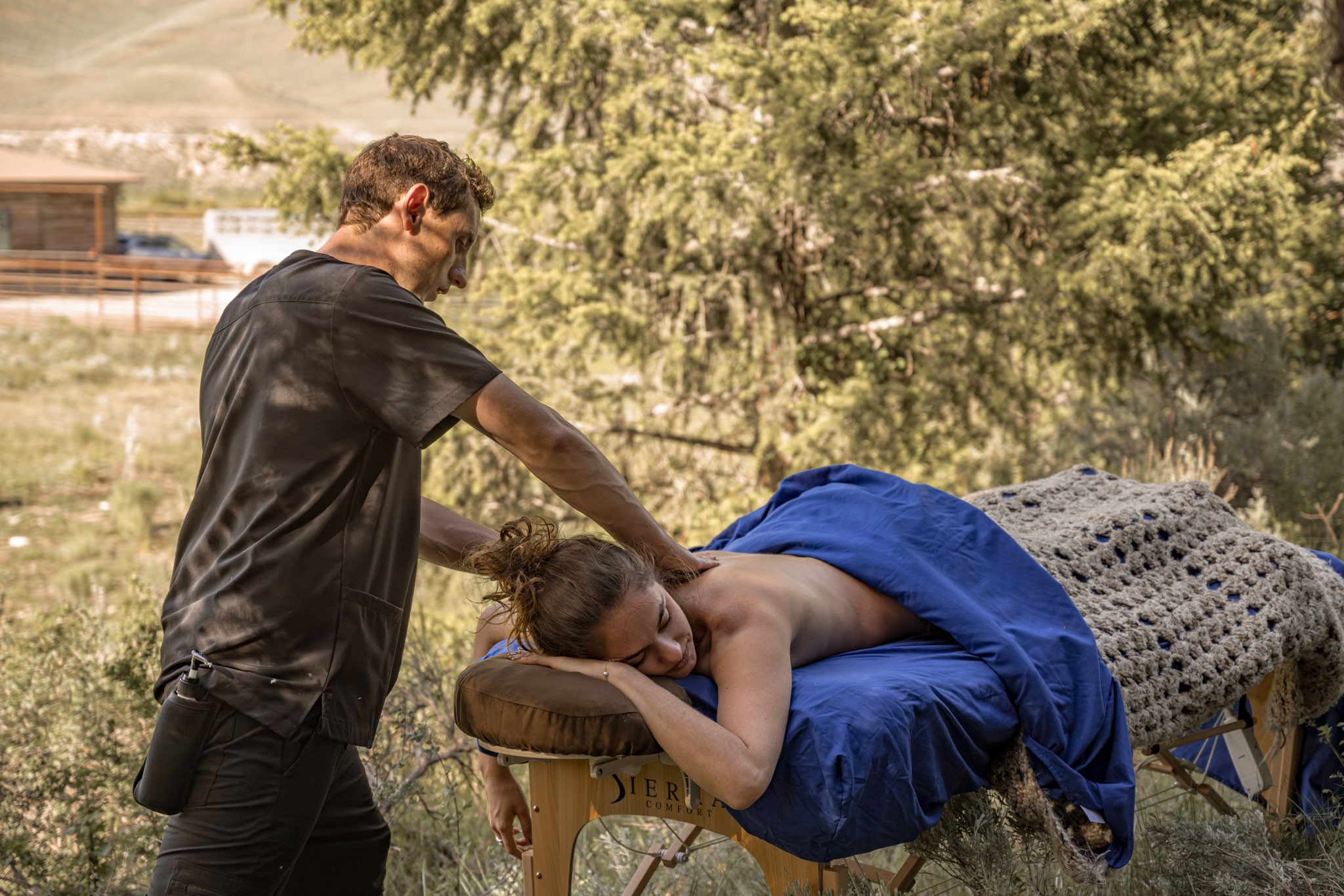 Massage therapist providing an outdoor massage session on a portable table